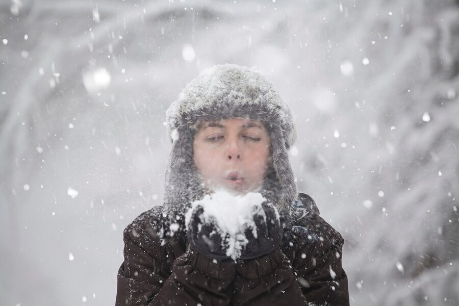 man blowing on snowball during winter